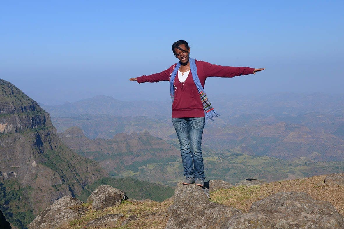 Visitor with outstretched arms at a mountain viewpoint