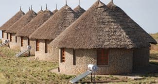 Stone tukuls with thatched roofs and solar water heaters