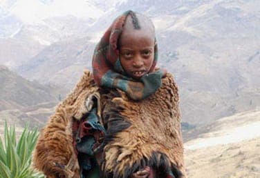 በበግ ቆዳ ካባ የተጠቀለለ ልጅ